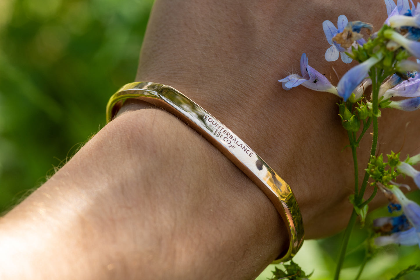 A 15 ton Counterbalance bracelet displayed on a model by Montana wildflowers.