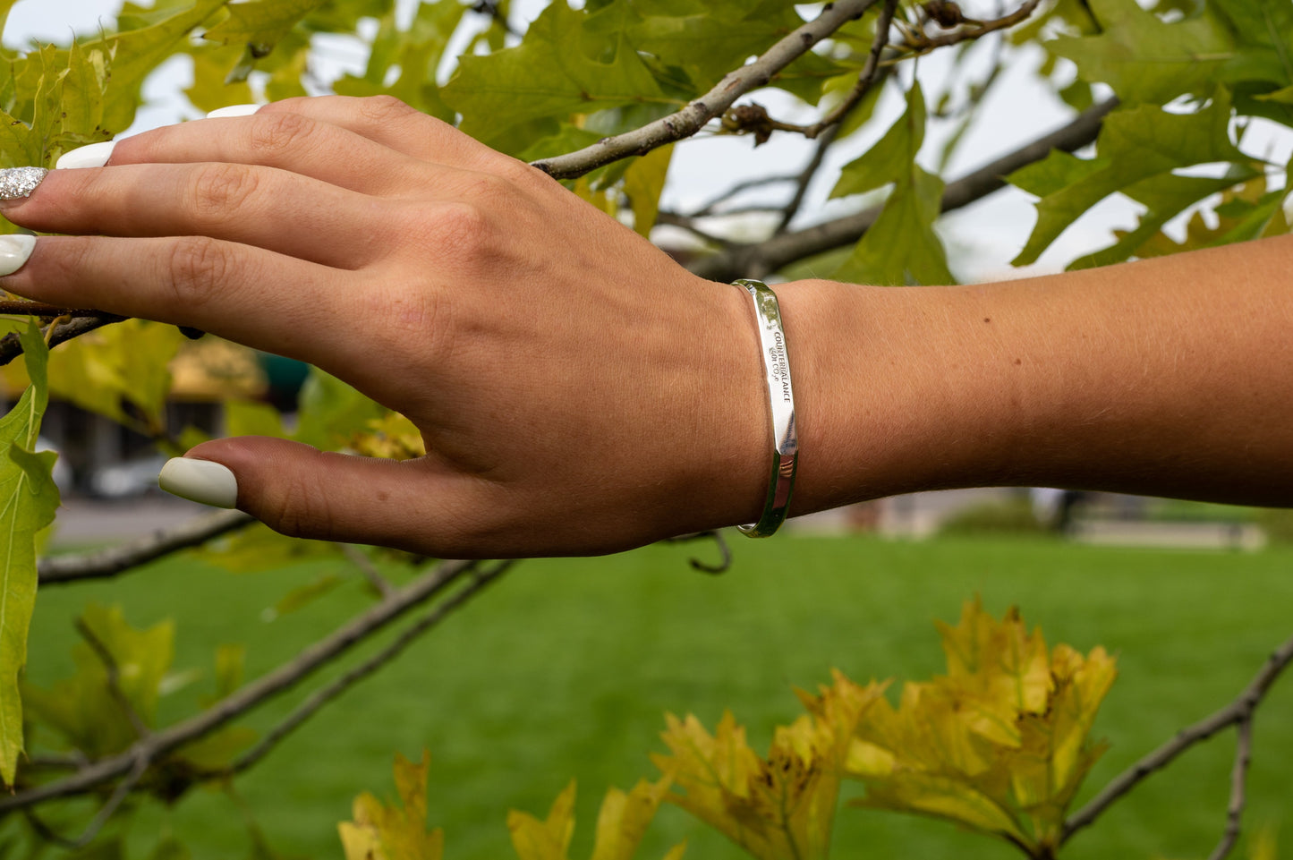 A model wears the white gold counterbalance while resting their hand upon a tree branch.