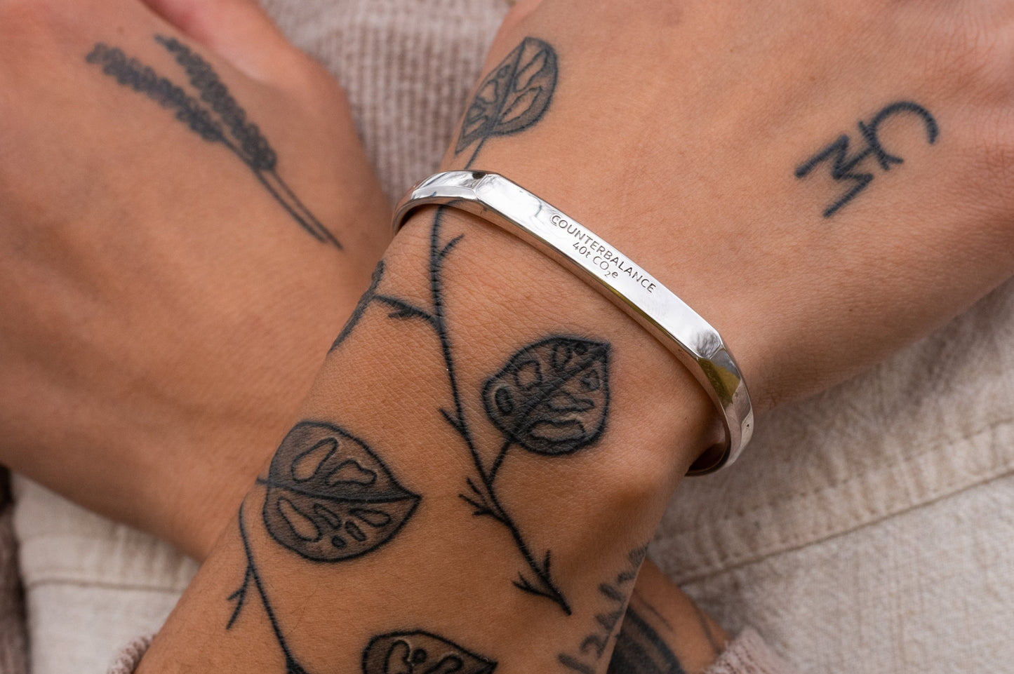 A model wears the white gold counterbalance while crossing their arms.