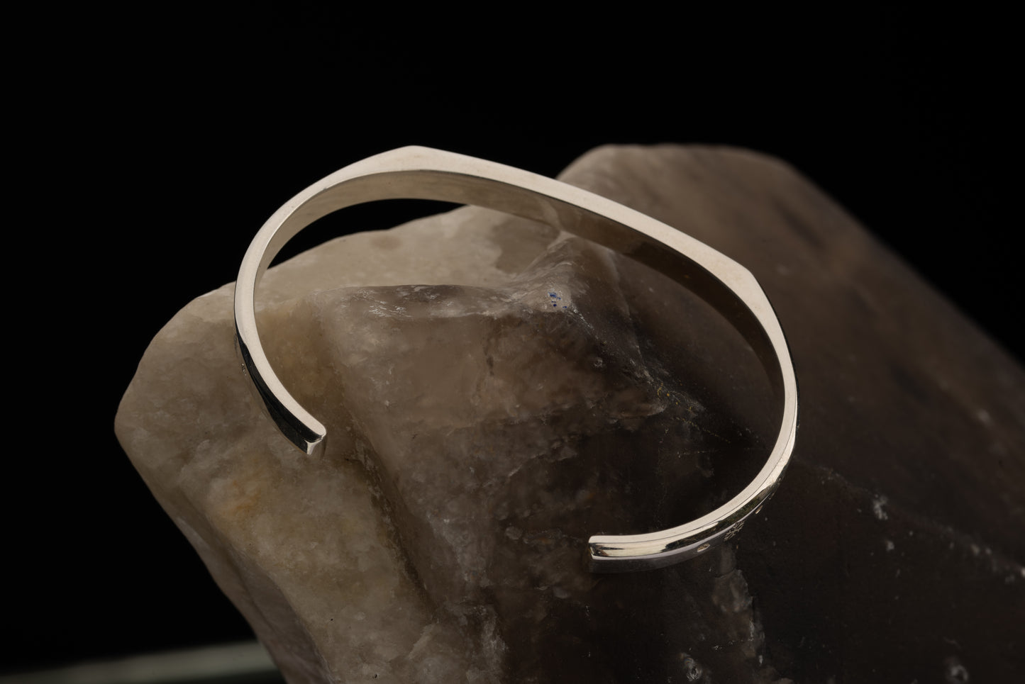 A silver counterbalance bracelet on a large quartz rock.