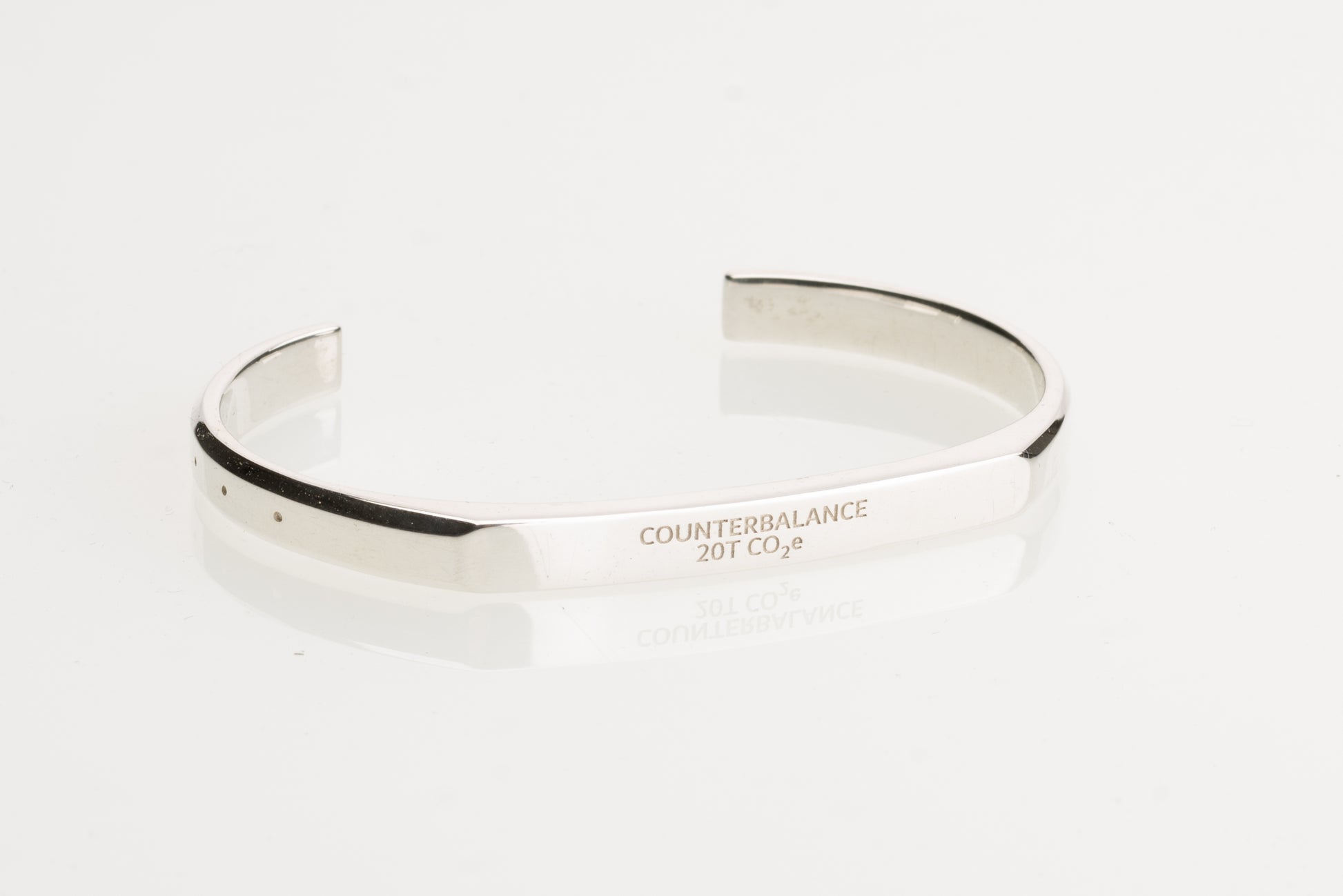 A silver counterbalance bracelet engraved with the word Counterbalance and the abbreviation 20t CO2e for 20 tons of carbon dioxide equivalent. The bracelet is displayed on a reflective white surface.