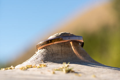 A rose gold counterbalance bracelet displayed upon piece of driftwood on the riverbank of the clark fork river. The bracelet is engraved with the word Counterbalance with the abbreviations and symbols for 30 tons of carbon dioxide equivalent below it.