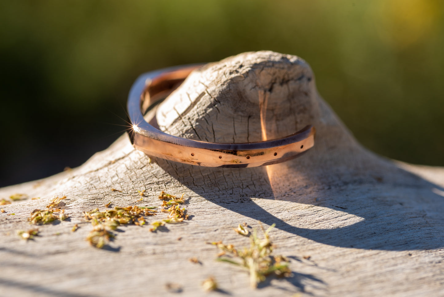 A rose gold counterbalance bracelet displayed upon piece of driftwood on the riverbank of the clark fork river. The bracelet is engraved with the word Counterbalance with the abbreviations and symbols for 30 tons of carbon dioxide equivalent below it.