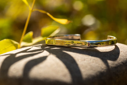 A silver counterbalance bracelet on a polished river rock. 