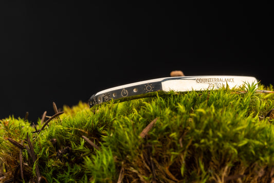 A 20 ton silver counterbalance bracelet displayed on a bed of moss.