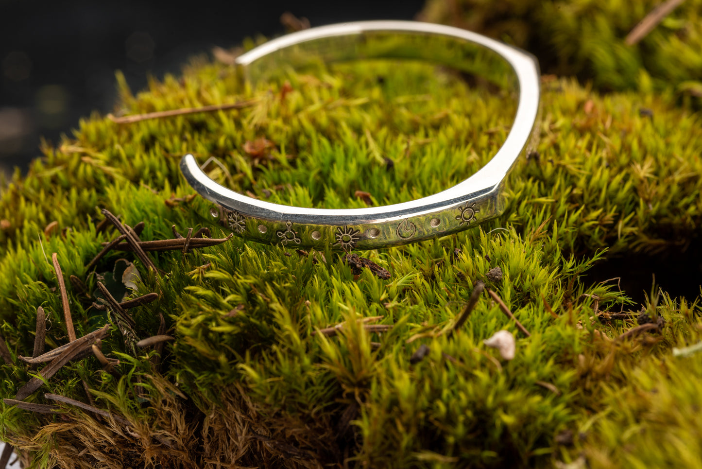 A 20 ton silver counterbalance bracelet displayed on a bed of moss.