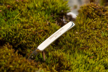 A 20 ton silver counterbalance bracelet displayed on a bed of moss.