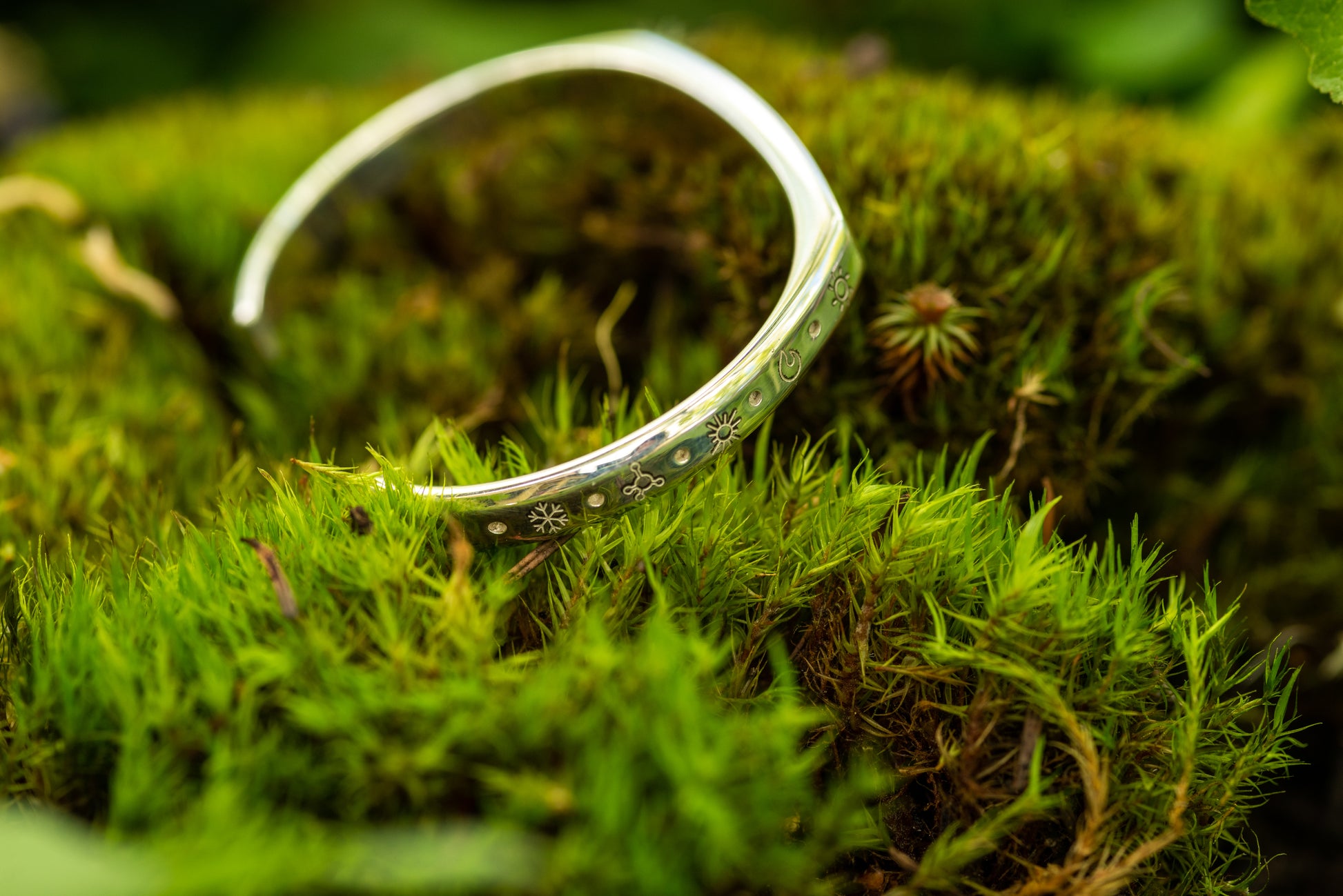 A 20 ton silver counterbalance bracelet displayed on a bed of moss.