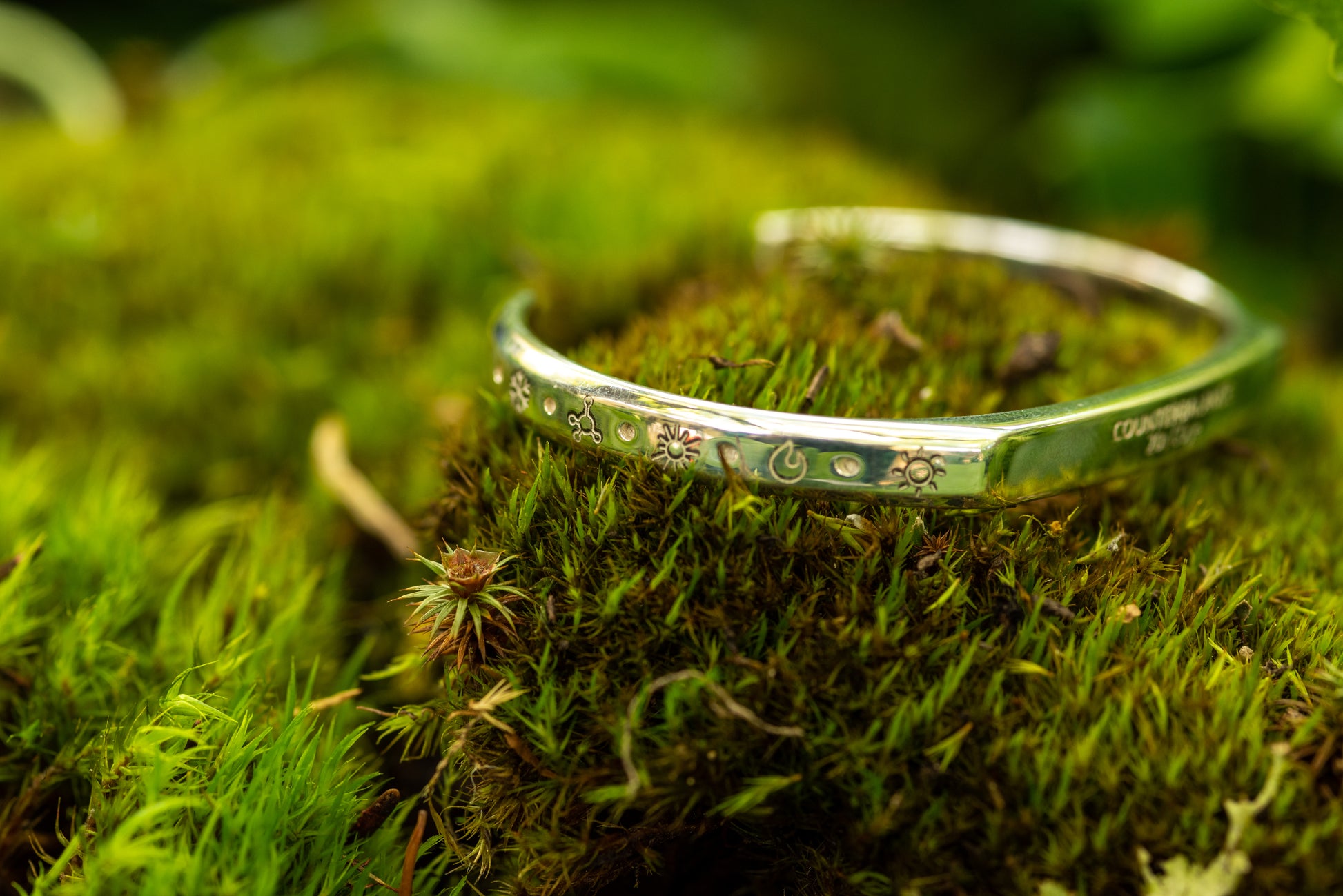 A 20 ton silver counterbalance bracelet displayed on a bed of moss.